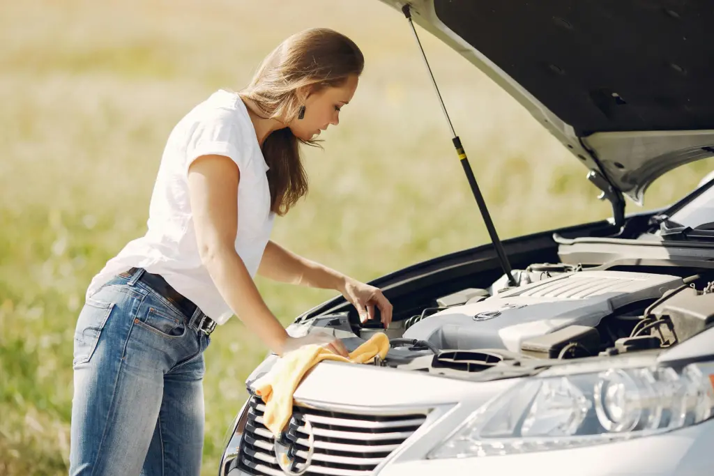 Troubled young woman near broken automobile in countryside during car accident