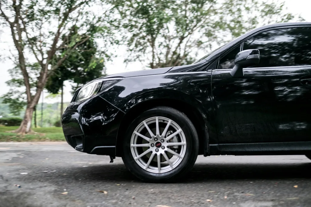 Sleek Black Car on Tree-Lined Roadway