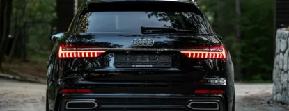 Sleek Black Luxury Car in Forest Driveway