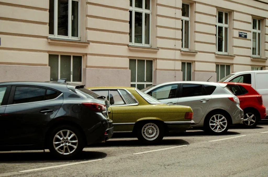 Several cars parked in a row along a building.