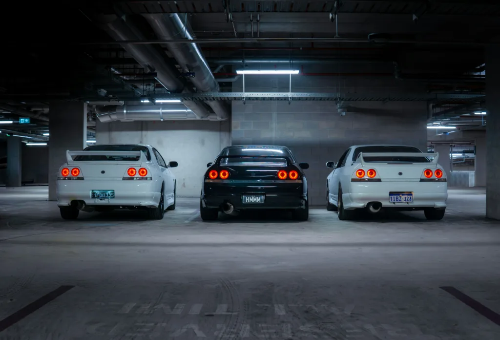 Three cars parked in a dimly lit garage.