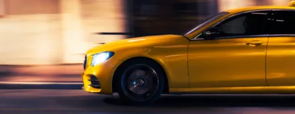 A yellow car speeds down a city street at night.