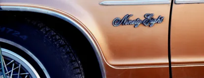 Close-up of an orange Oldsmobile Ninety-Eight showing vintage design details.