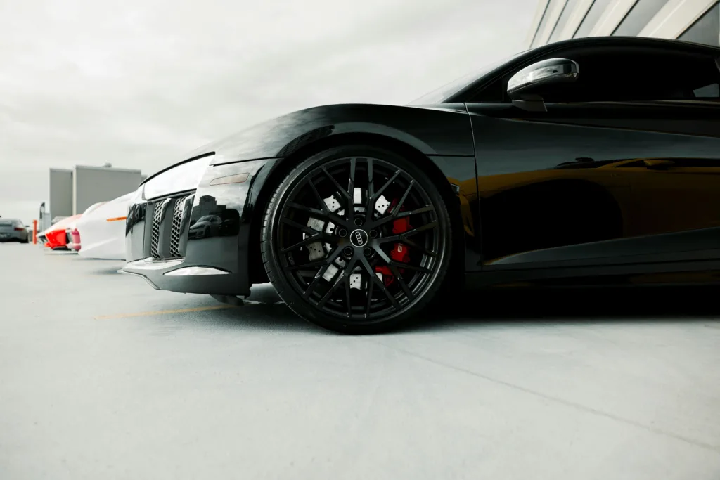 Close-up of a black luxury sports car's wheel detail in an outdoor setting.