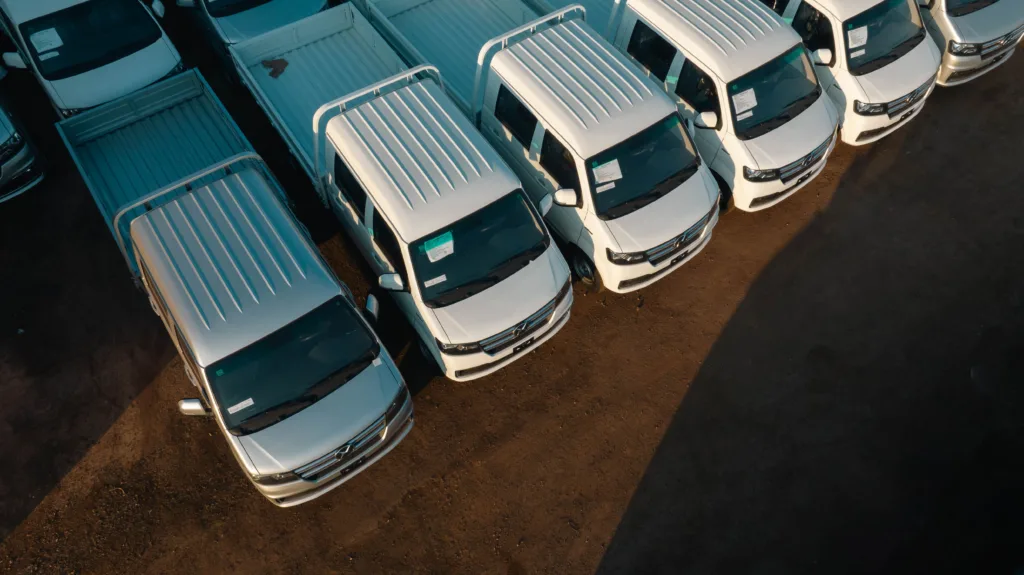 Aerial view of white pickup trucks aligned neatly in a parking lot.