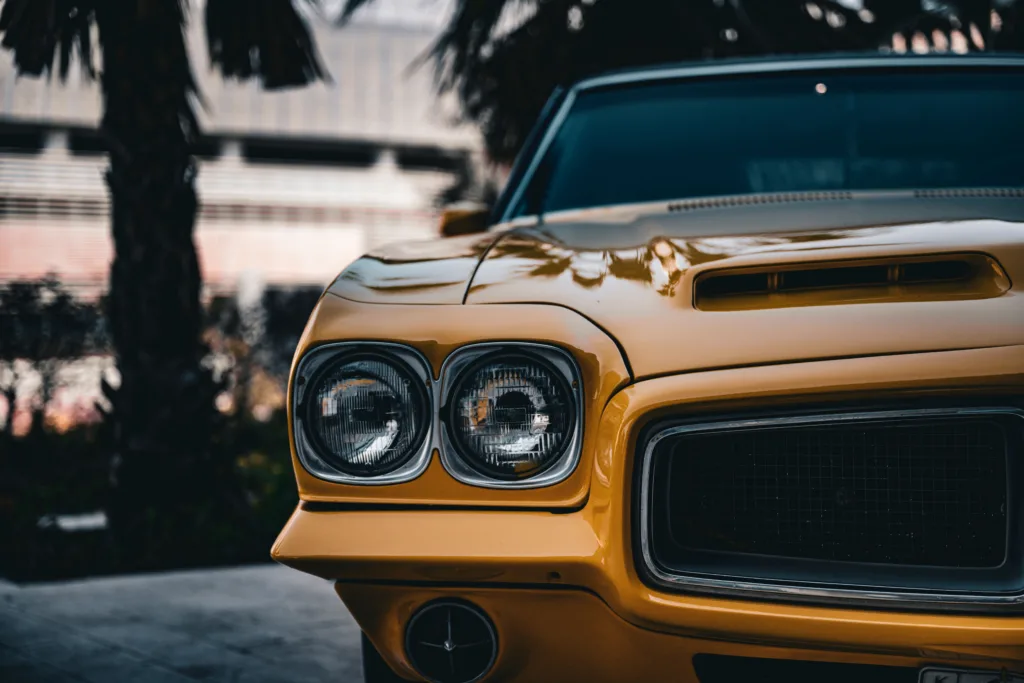 Close-up of a classic yellow sports car hood and headlight.
