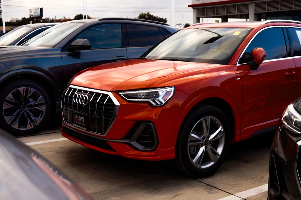 A vibrant orange SUV parked among other vehicles at a car dealership